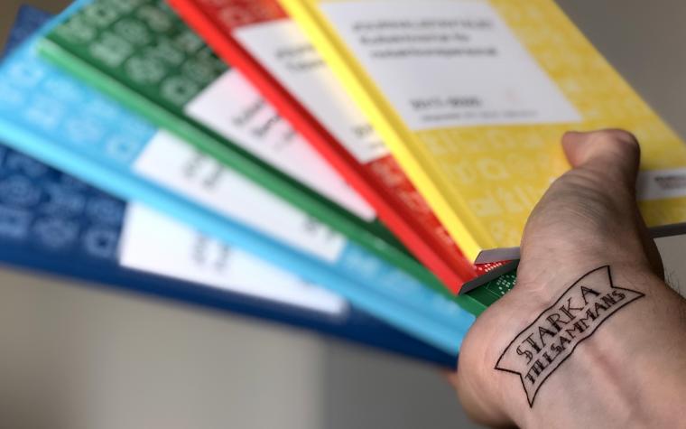 Hand med tatuering "Starka tillsammans" håller upp kollektivavtalen