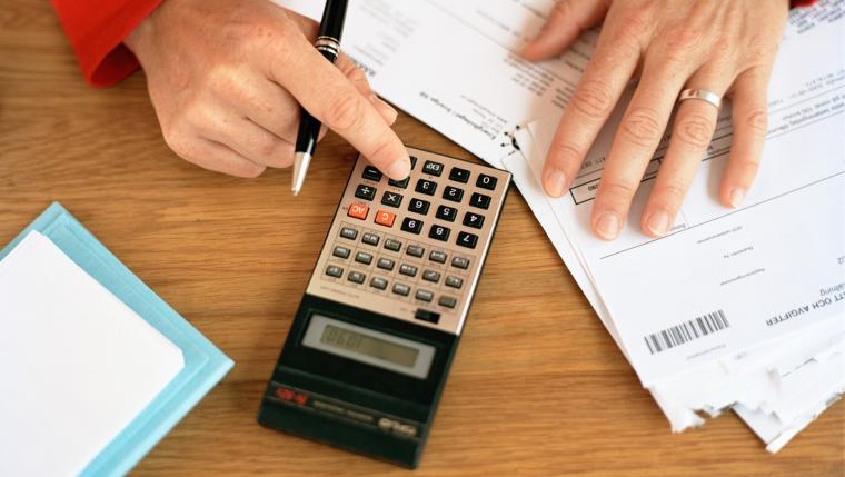 Person som sitter med miniräknare och räkningar