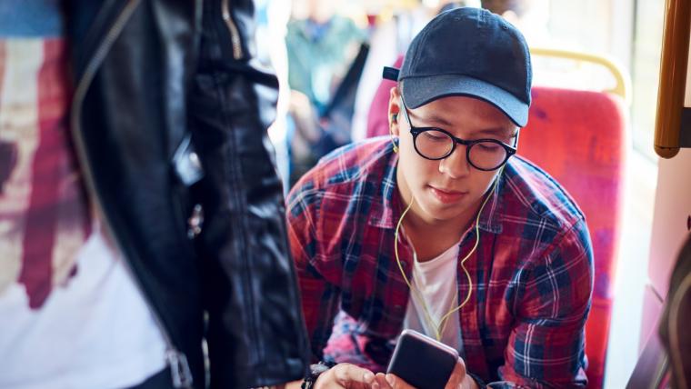 Ung man i hörlurar lyssnar på musik via mobilen